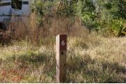 Close-up photo of the brown with white site number sign on a wooden post.