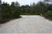 This photo shows an RV and vehicle on the fine gravel pad. There is vegetation with some trees surrounding the site.