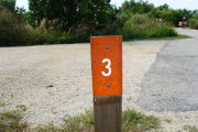 Photo: 003, View of site number post white on brown, bushes visible in the back ground.