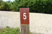 Photo: 005, View of site number post white on brown, bushes visible in the back ground.
