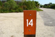 Photo: 014, View of site number post white on brown, bushes visible in the back ground.
