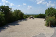 Photo: 016, View of gravel campsite with picnic table and grill, Atlantic Ocean and bushes in background.