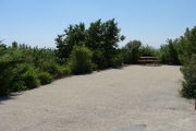 Photo: 021, View of gravel campsite with picnic table and grill, bushes and Atlantic Ocean in background.