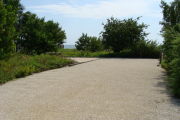Photo: 023, View of gravel campsite with picnic table and grill, Atlantic Ocean and bushes in background.