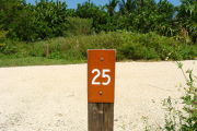 Photo: 025, View of site number post white on brown, bushes visible in the background.