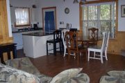 The main living area of the cabin offers two comfortable couches, and a wooden dining table with four wood chairs. An electric fireplace can be operated year round and can give off heat or be set so you can just watch the flames flicker. In the modern kitchen there is a dish washer, micro wave oven, stove, big refrigerator and an automatic coffee maker. Not seen are the two bedrooms and bathroom.