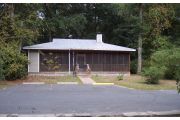 From this view you see the front of the cabin which is nestled on three sides in the woods. An L shaped screened porch runs across most of the front of the cabin and then turns and runs to the end of the side of the cabin. On the porch are two rocking chairs, a porch swing and a picnic table. There are two doors leading into the cabin proper. One is to the front of the cabin and the other one is to the kitchen, near the back of the cabin. There is rear screen door that leads to the back outside area of the cabin.