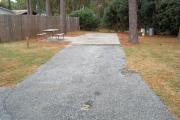 A view of RV site two at Topsail Hill Preserve State Park looking towards the back of the site.  A picnic table is on a concrete pad to the left of the site and the utility boxes are to the right.