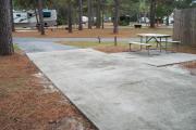 A view of RV site two at Topsail Hill Preserve State Park looking towards the front of the site.  A picnic table is on a concrete pad to the right of the site.