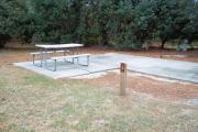 A view of RV site three at Topsail Hill Preserve State Park showing the site marker, picnic table, and utility hook up boxes.