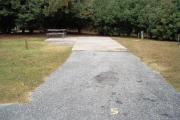 A view of RV site five at Topsail Hill Preserve State Park looking towards the back of the site.  A picnic table is on a concrete pad to the left of the site and utility hook up boxes are to the right.