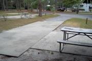 A view of RV site five at Topsail Hill Preserve State Park looking towards the front of the site.  A picnic table is on a concrete pad to the right of the site.  Other RV sites can be seen to the left of the site.
