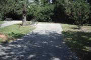 A view of RV site six at Topsail Hill Preserve State Park looking towards the back of the site.  A picnic table is on a concrete pad to the left of the site.