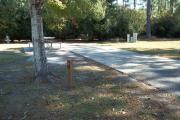 A view of RV site seven at Topsail Hill Preserve State Park showing the site marker, a picnic table next to the site to the left, and the utility hook up boxes to the right.