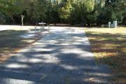 A view of RV site seven at Topsail Hill Preserve State Park looking towards the back of the site.  A picnic table is on a concrete pad to the left of the site and utility hook up boxes are to the right.