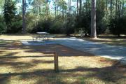 A view of RV site eight at Topsail Hill Preserve State Park showing the site marker, a picnic table next to the site to the left, and the utility hook up boxes to the right.
