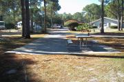 A view of RV site eight at Topsail Hill Preserve State Park looking towards the front of the site.  A picnic table is on a concrete pad to the right of the site.  The bathhouse and other RV sites are visible in the background.