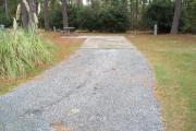 A view of RV site nine at Topsail Hill Preserve State Park looking towards the back of the site.  A picnic table is on a concrete pad to the left of the site and utility hook up boxes are to the right.