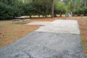 A view of RV sites eleven at Topsail Hill Preserve State Park looking towards the back of the site.  A picnic table is next to a concrete pad to the left of the site and utility hook up boxes are to the back of the site.