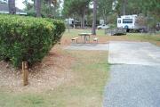 A view of RV site nineteen at Topsail Hill Preserve State Park showing the site marker and a picnic table to the left of the site.  A small wooden bridge and other RV sites are visible in the background.