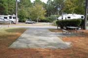 A view of RV site nineteen at Topsail Hill Preserve State Park looking towards the front of the site.  A picnic table is next to a concrete pad to the right of the site.  Other RV sites are visible in the background.