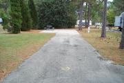 A view of RV site twenty-nine at Topsail Hill Preserve State Park looking towards the back of the site.  A picnic table is on a concrete pad to the left of the site and utility hook ups are to the right of the site.
