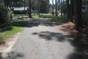 A view of RV site thirty at Topsail Hill Preserve State Park looking towards the back of the site.  A picnic table is on a concrete pad to the left of the site and utility hook ups are to the right of the site.