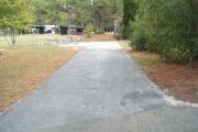 A view of RV site thirty-one at Topsail Hill Preserve State Park looking towards the back of the site.  A picnic table is on a concrete pad to the left of the site and a small wooden dock is visible in the background.