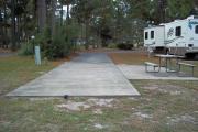 A view of RV site thirty-one at Topsail Hill Preserve State Park looking towards the front of the site.  A picnic table is on a concrete pad to the right of the site and the utility hook ups are to the left.
