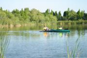 Father and sons fishing from kayaks on a scenic lake.