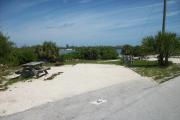 The back has a view of the inlet. The front is open to the street. There is a gravel drive in the center of the site. A picnic table and fire ring is on the left. The right side has an open grassy area.