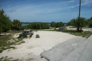 The back has a view of the inlet. The front is open to the street. There is a gravel drive in the center of the site. The left side has a picnic table and a fire ring.
