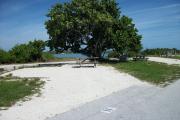 The back has a view of the inlet. The front is open to the street. There is a gravel drive in the center of the site.  The right side has a picnic table shaded by a magnificent sea grape.