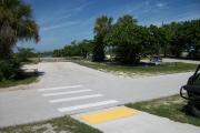 The campsite is handicap accessible. The front is open to the street and the back faces a street.  There is a gravel drive in the center of the site. There is a crosswalk in front of the site. Trees are on both sides of the site.