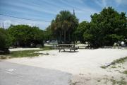 The front is open to the street and the back faces a street. There is a gravel drive in the center of the site. There are palms and sea grapes at the back of the site.