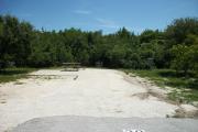 The front of is open to the street.  The back has abundant native plants. There is a gravel drive in the center of the site.  A picnic table sits on the left.