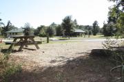 Photo: 010, SANTOS CAMPGROUND. View of campsite with water and electric hookups and picnic table with fire ring. Campground facilities can be seen nearby.