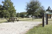 Photo: 011, SANTOS CAMPGROUND. View of campsite with water and electric hookups and picnic table with fire ring. Restrooms can be seen.